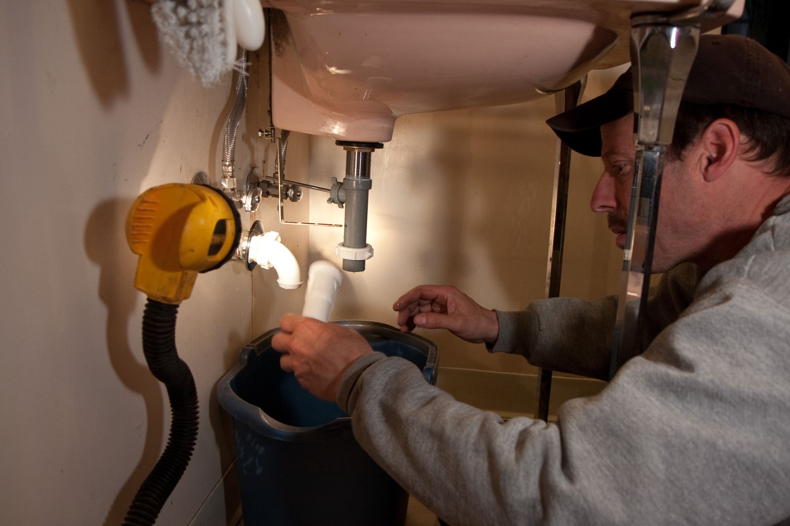 A plumber repairing pipes under a sink, the everyday work Wilson Plumbing is called for.